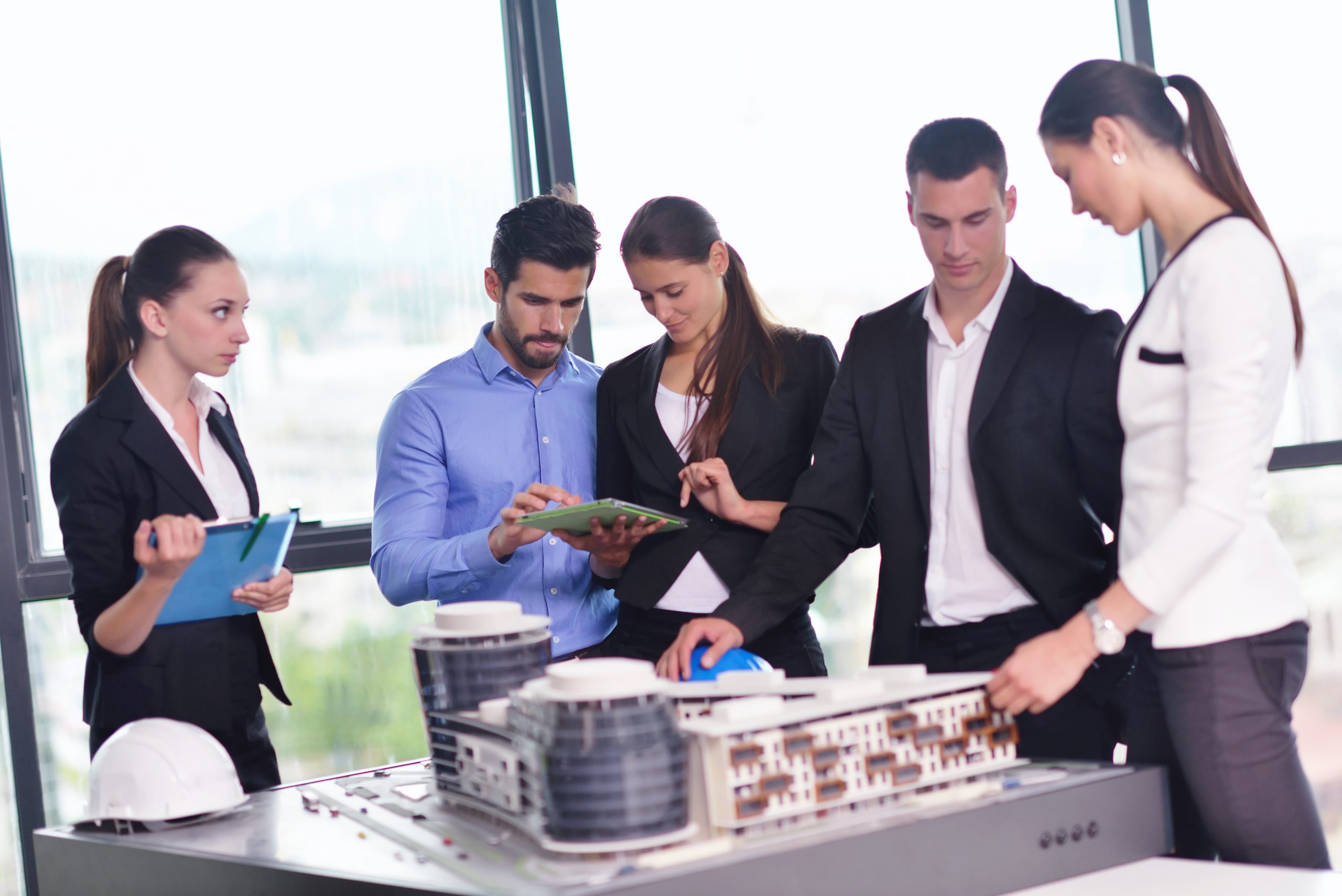 business people group on meeting and presentation  in bright modern office with construction engineer architect and worker looking building model and blueprint planbleprint plans
