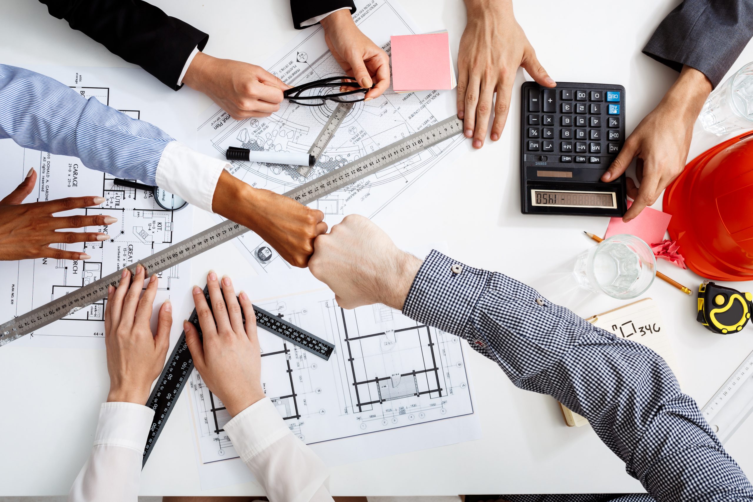 Picture of businessmen's hands on white table with documents, coffee and drafts