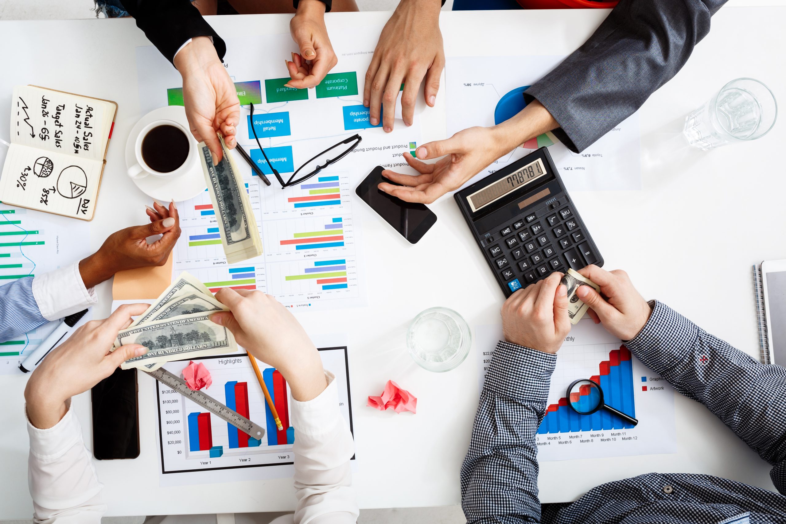 Picture of businessmen's hands on white table with documents, coffee and drafts
