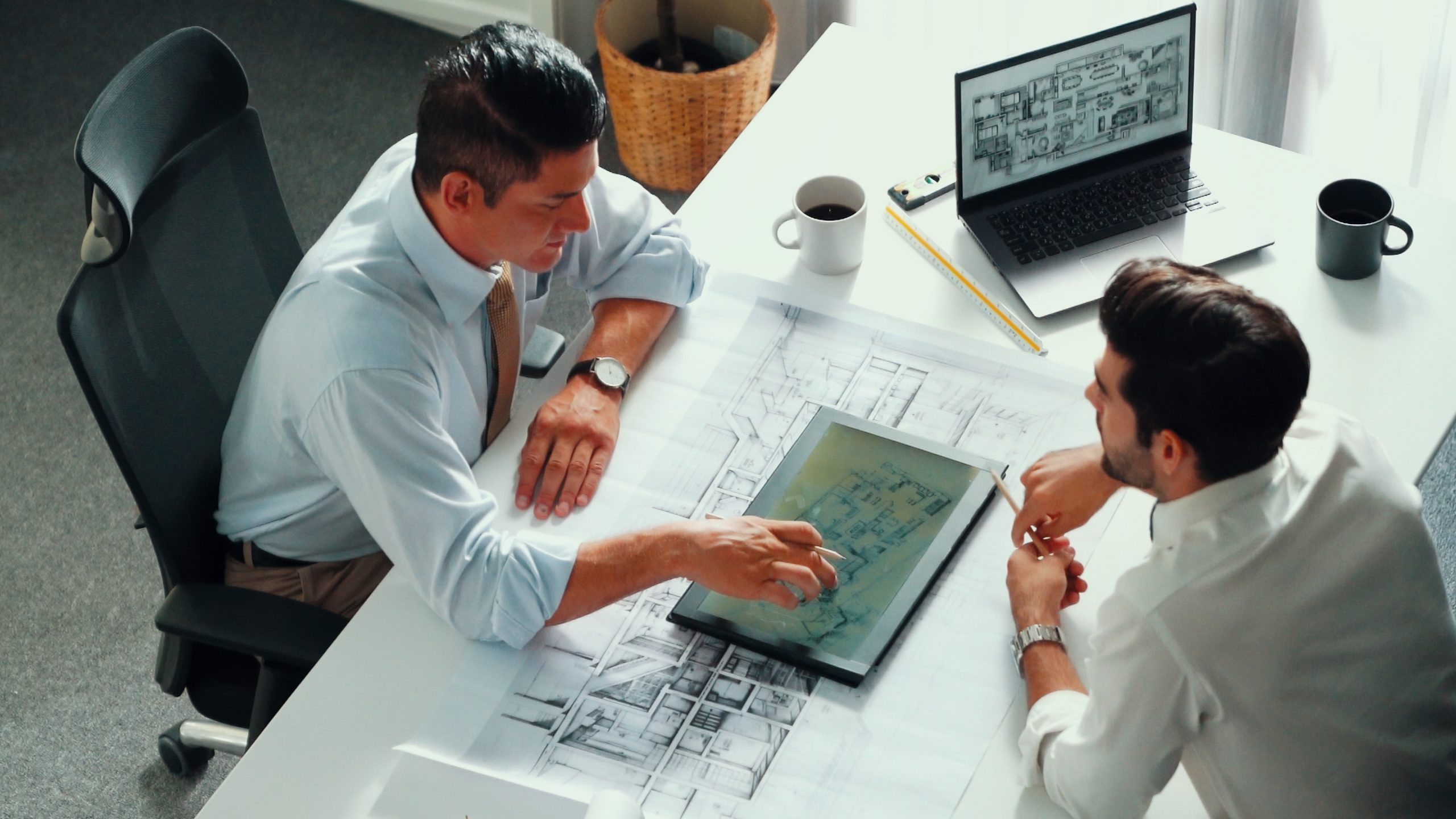 Top view of manager talk and discussing about house construction while sit and write at blueprint at meeting table with project plan laptop displayed house construction and equipment. Alimentation.